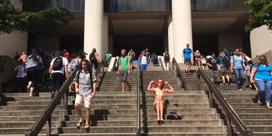 Studentin sitzt nackt vor Bibliothek