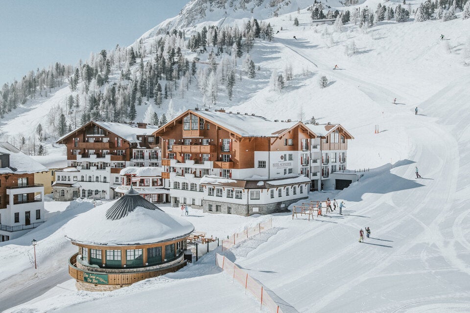 Mit dem 1. Platz beim pistenhotels.info Award 2026 sichert sich das Hotel Schneider in Obertauern den Spitzenrang unter allen Pistenhotels Europas. Das traditionsreiche 4-Sterne-Superior-Haus wird seit seiner Gründung im Jahr 1967 von Familie Schneider mit viel Leidenschaft geführt und überzeugt durch seine erstklassige Lage direkt an der Piste im schneesicheren Skigebiet Obertauern. Gäste genießen höchsten Komfort und Service, angefangen beim luxuriösen Skiraum mit eigenem Aufzug direkt auf die Piste bis hin zum stilvollen Wellnessbereich mit Hallenbad, Whirlpool und verschiedenen Saunen, der nach einem Tag im Schnee zum Entspannen einlädt. 