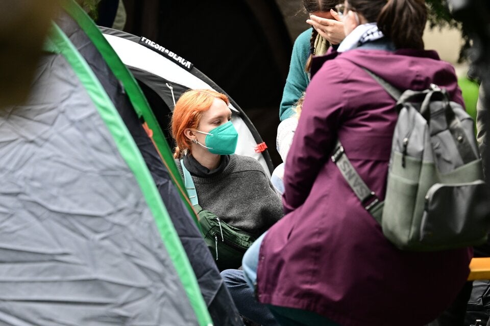 Prostest-Camperin mit Corona-Maske blickt aus ihrem kleinen Zelt.