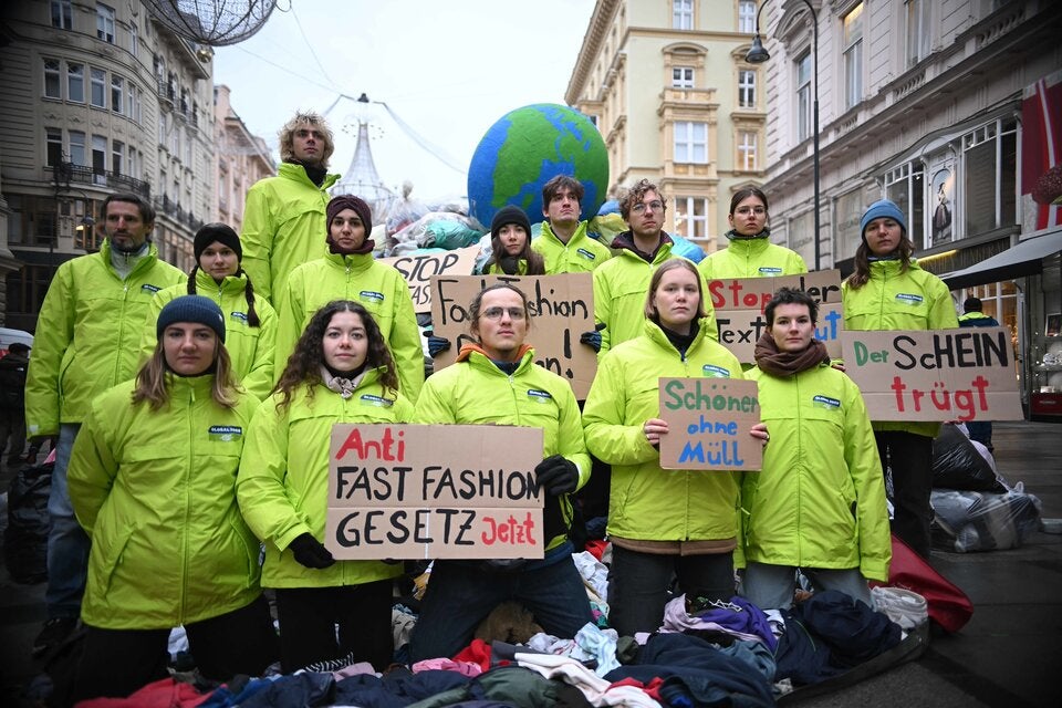 NGOs prangern mit einem Berg aus Textilmüll Wegwerfkleidung an und werben für nachhaltige Mode.