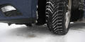 Ein Auto-Winterreifen auf schneeglatter Fahrbahn