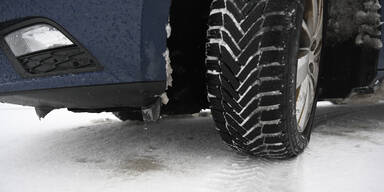 Ein Auto-Winterreifen auf schneeglatter Fahrbahn