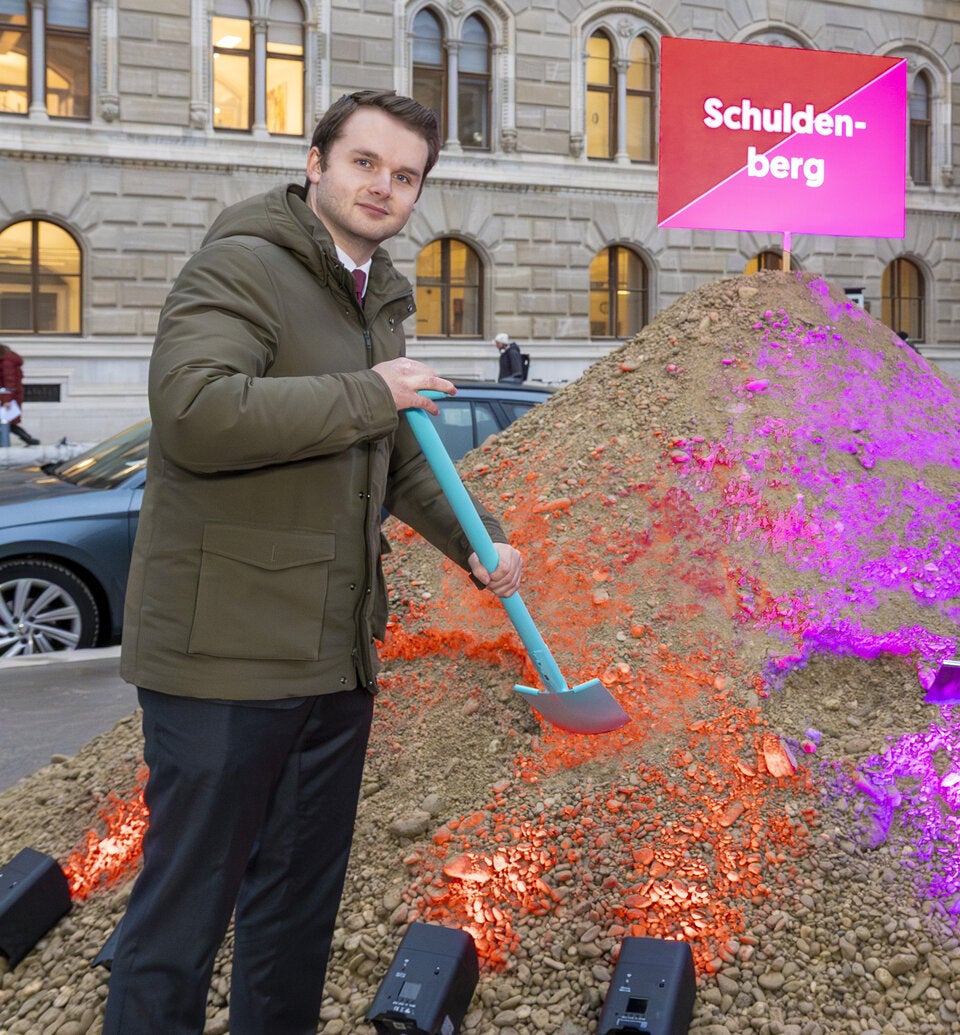 Zierfuß steht vor einem rot-pinken Schulden, fährt aber Audi A6. 