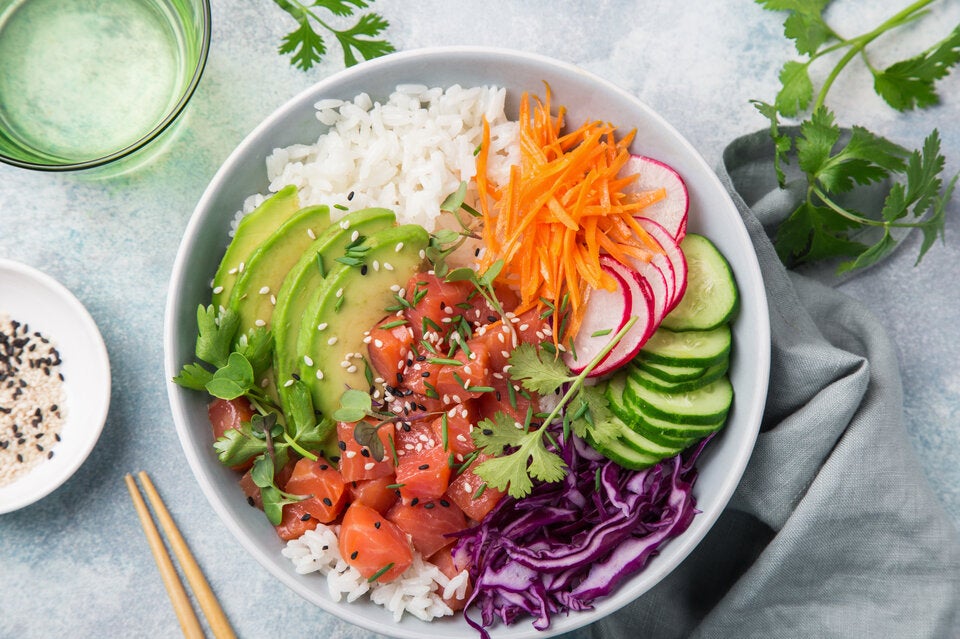 Poke Bowl mit rotem Reis, Gemüse und Lachs.