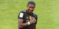 David Alaba greift mit der Hand auf das Bayern-Logo