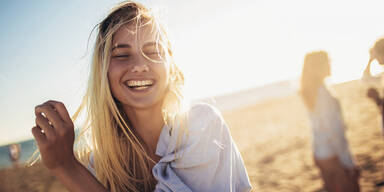 L&auml;chelnde Frau am Strand
