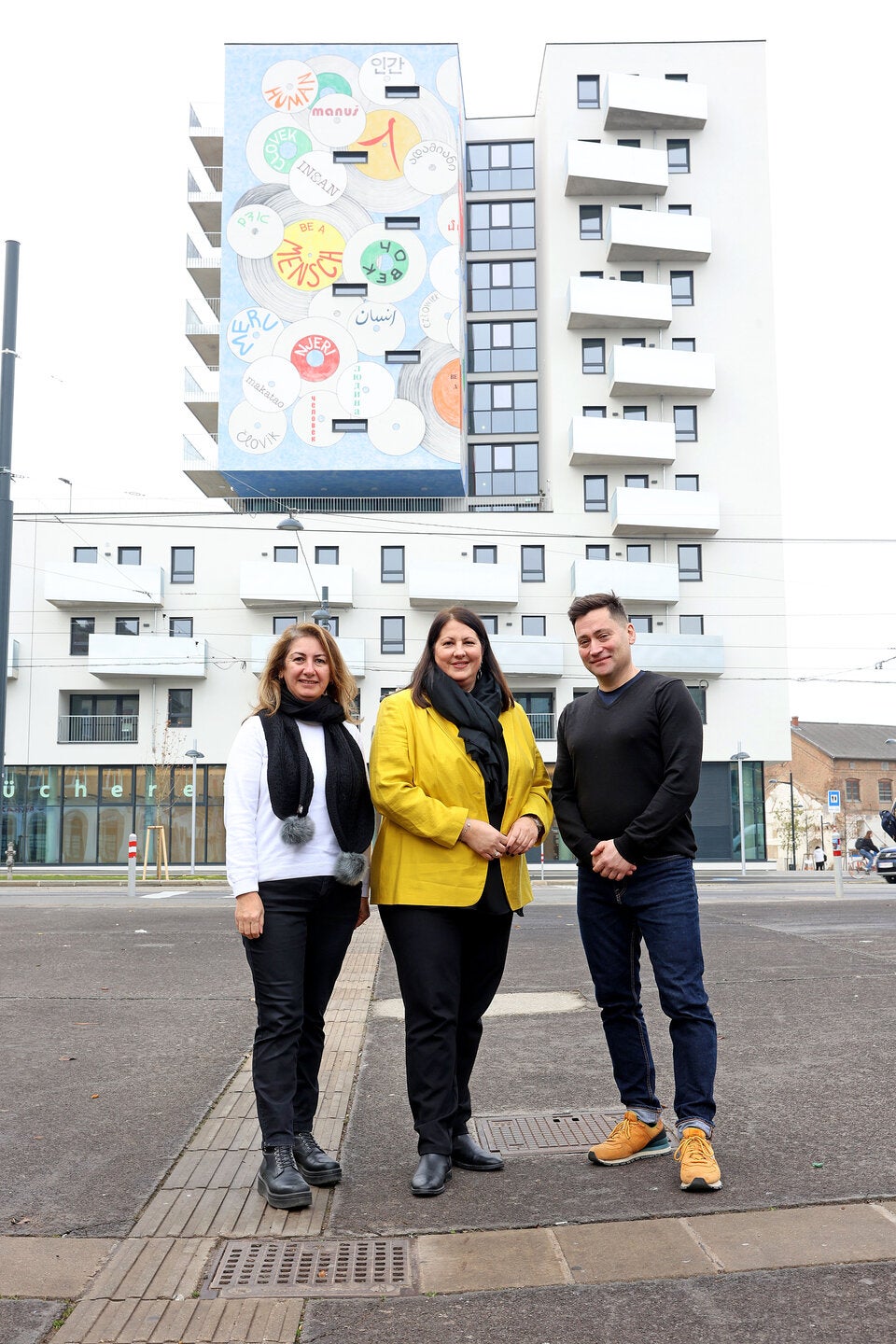 Ebru Ayas und Burak Büyük vom Nachbarschaftsservice wohnpartner_wien mit Vizebürgermeisterin und Wohnbaustadträtin Kathrin Gaál vor dem neuen Gemeindebau an der Laxenburger Straße.