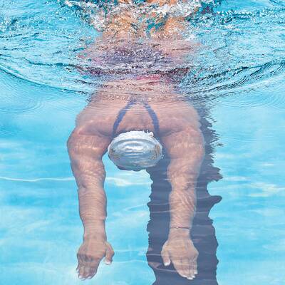 4. Der Kopf wird durch die Bewegung automatisch hinausgedrückt (atmen!). Die Arme haben die Ruderbewegung nach innen abgeschlossen. Zeitversetzt startet jetzt die Beinbewegung. Achten Sie darauf, die Beine gleichmäßig zu bewegen. 