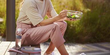 Frau sitzt drau&szlig;en und isst