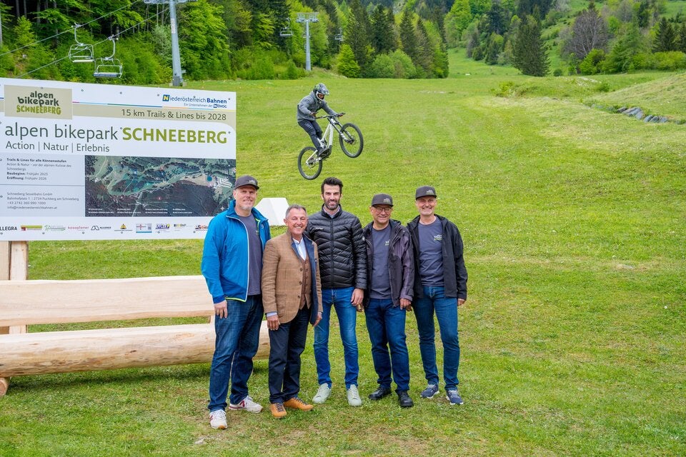 Die NÖVOG Geschäftsführer Michael Hasenöhrl und Wolfgang Schroll (außen links & rechts), Puchbergs Bürgermeister Christian Dungl, LH-Stellvertreter Udo Landbauer und der Geschäftsführer der Schneeberg Sesselbahn Hubert Resch haben gemeinsam mit dem Markenbotschafter Clemens Kaudela (am Bike) den Startschuss für den Baubeginn des Alpen Bikeparks Schneeberg gegeben.