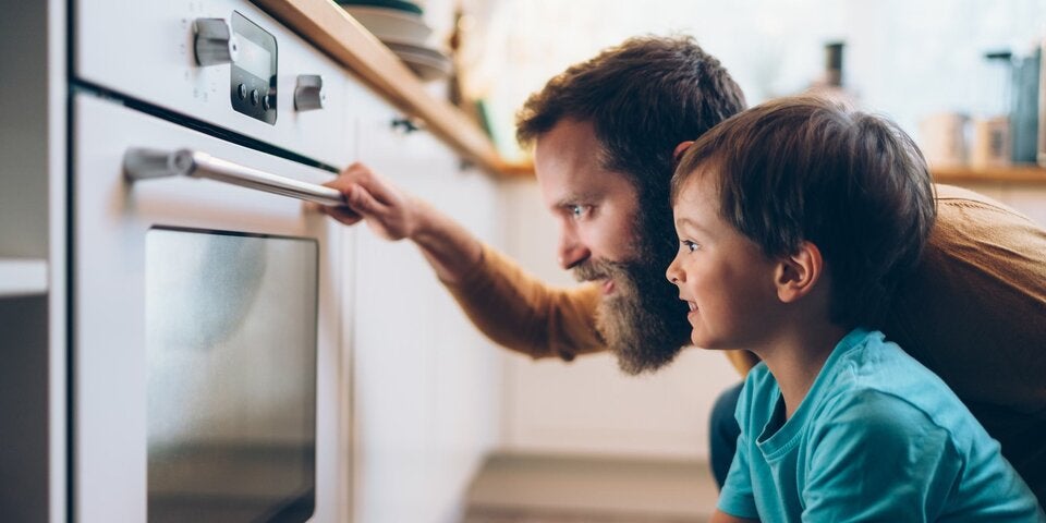 Vater schaut mit Sohn in den Ofen