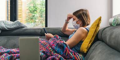 Frau mit Maske auf der Couch