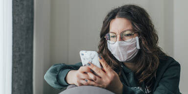 Frau mit Maske t&auml;tigt einen Anruf