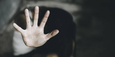 Frau hält die Hand gegen ihren Angreifer um sich zu schützen