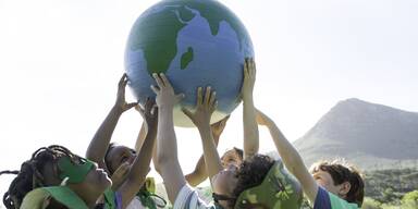 Kinder die eine Weltkugel halten