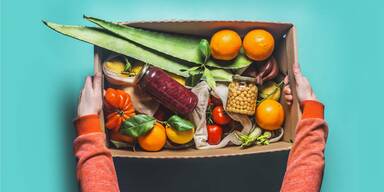 Frau h&auml;lt Papierbox mit pflanzlichen Lebensmittel