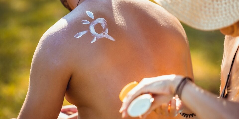 Frau zeichnet mit Sonnencreme auf Mann