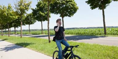 Mann f&auml;hrt Fahrrad im Gr&uuml;nen