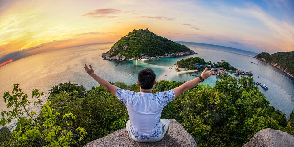 Mann sitzt auf einem Felsen in Thailand