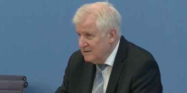 Horst Seehofer bei Pressekonferenz vor blauem Hintergrund