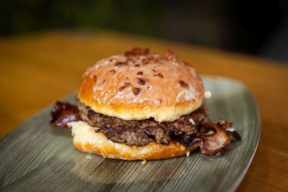 BBQ-Krapfen: frisch gebackenen Krapfen mit Ahorn-Speckglasur, Marillenmarmelade, knusprigem Bacon, einem saftigen Rindfleisch-Patty und einer extra rauchigen BBQ-Sauce.