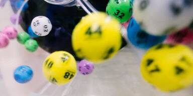Bunte Lottokugeln fliegen durch die Luft.