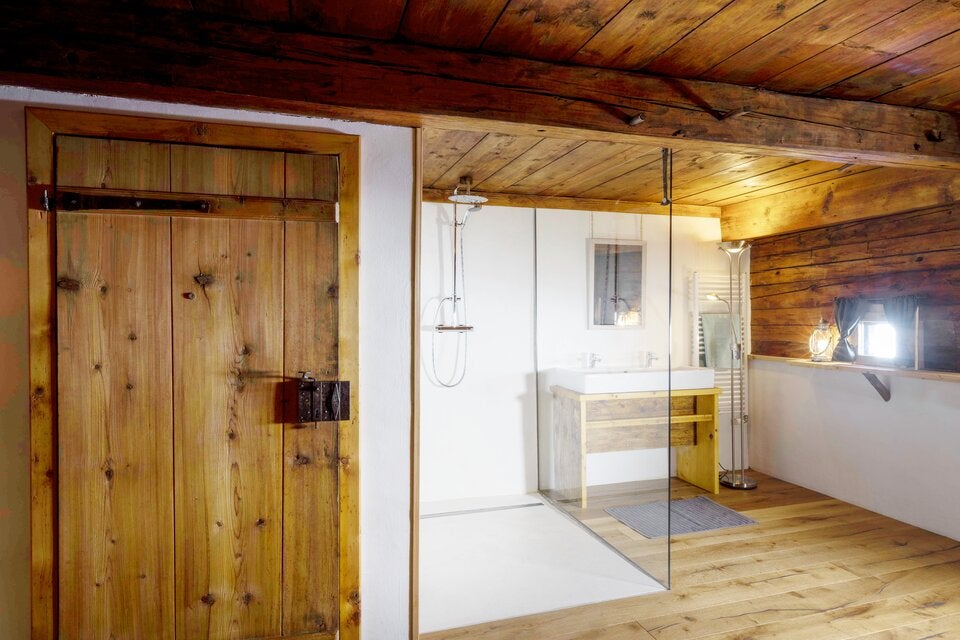 Rustikal, aber modern ist auch das Badezimmer mit großer Dusche unter der schönen Holzdecke.