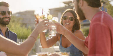 Menschen sto&szlig;en mit Getr&auml;nken an