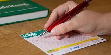 Lotto-Schein mit Hand und Kugelbschreiber