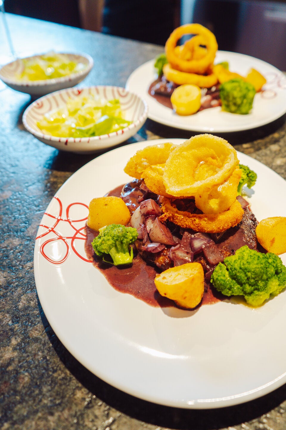 Zwiebelrostbraten mit Zwiebelringen und frittierten Erdäpfeln