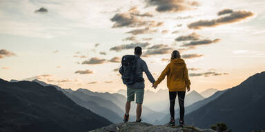 Paar steht auf einem Berg und genie&szlig;t die Landschaft