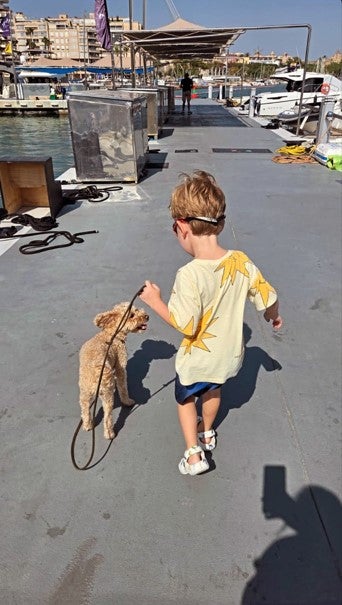 Kurz-Sohn Konstantin spielt im Hafen mit einem kleinen Hund.