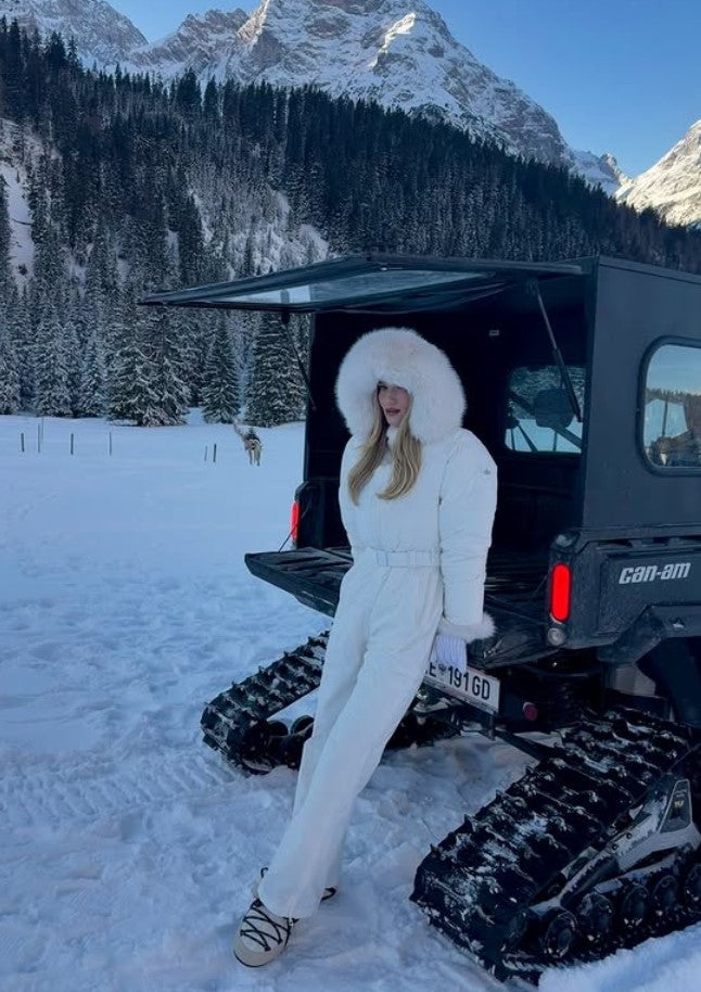 Rosie lehnt an einer Pistenraupe mit Tiroler Kennzeichen