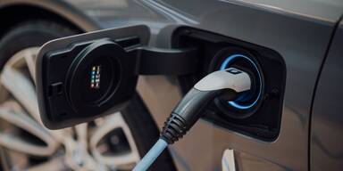 Graues Fahrzeug mit angekoppeltem Elektrotankkabel.