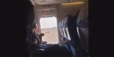 Frau &ouml;ffnet Notausgangst&uuml;r Flugzeug