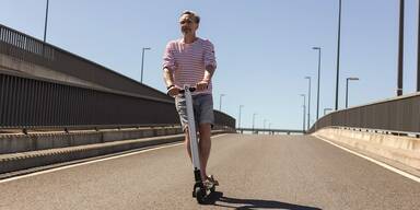 Mann mit E-Scooter auf leerer Straßenausfahrt