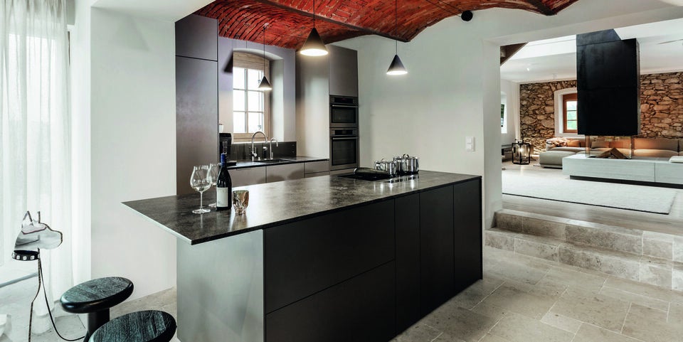 Die moderne Küche mit freistehendem Herd unter dem Original-Gewölbe und das Wohnzimmer mit maßgefertigtem Kamin fügen sich zu einem Landhaus-Traum zusammen.