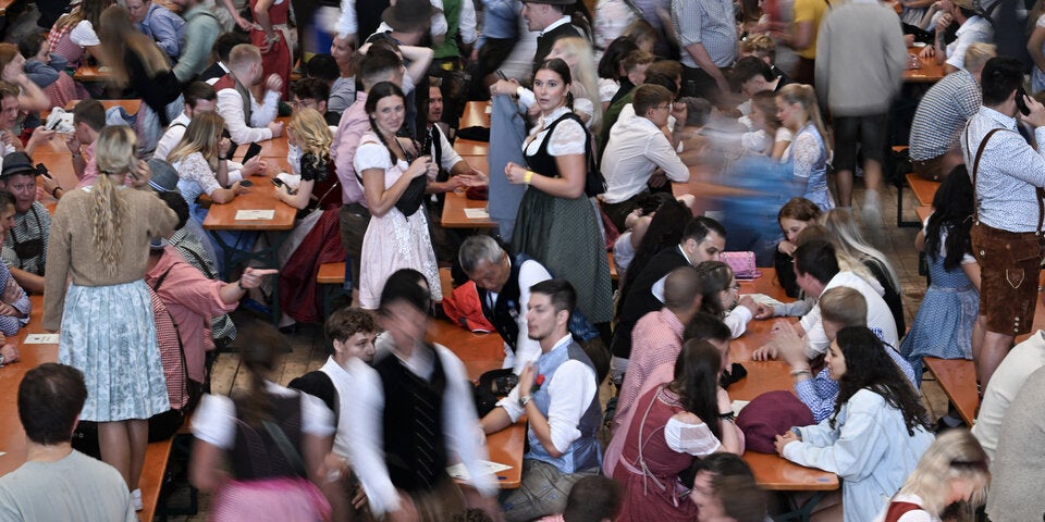 Die ersten Wiesn-Besucher 2023 nehmen in einem Festzelt Platz.