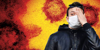 Mann mit Maske hält Hand vor den Kopf