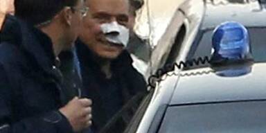 Berlusconi mit verbundenem Gesicht heim