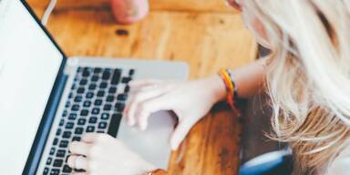 Laptoptastatur mit blonder Frau, die eben etwas eingibt.