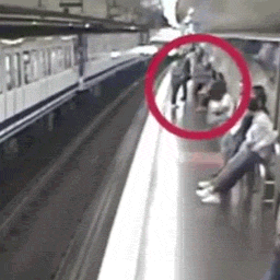 Frau starrt auf ihr Handy und fällt auf Gleis