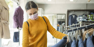 Frau mit Maske in einem Bekleidungsgeschäft