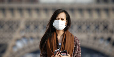 Frau vor Eiffelturm mit Maske