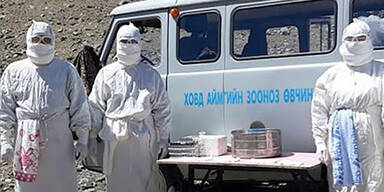 Menschen in Schutzanzug vor Bus