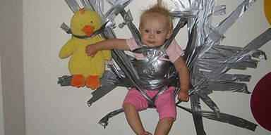 Mutter klebt kleinen Sohn an die Wand